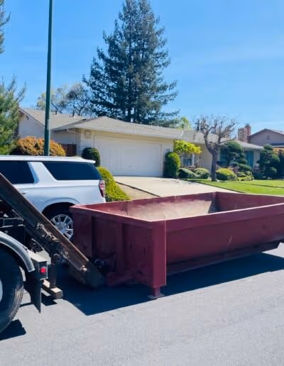 Roll-off dumpster being delivered to residential driveway